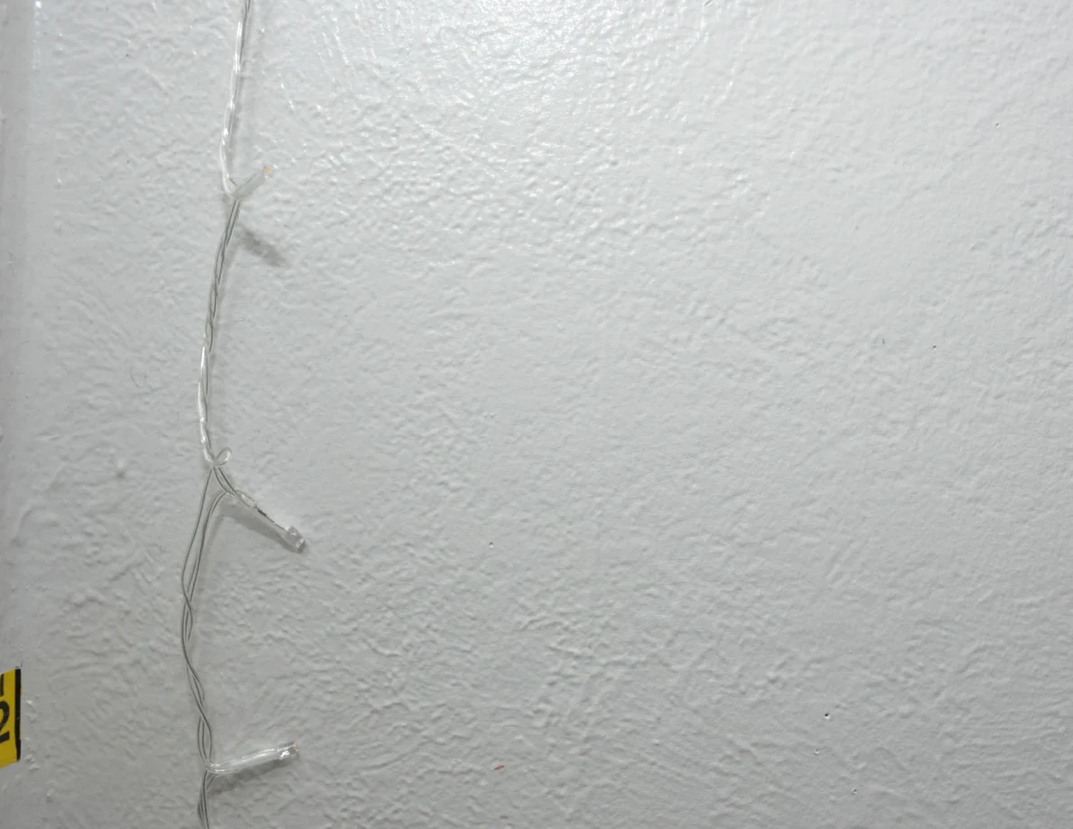 String-light cable against a pale textured wall.