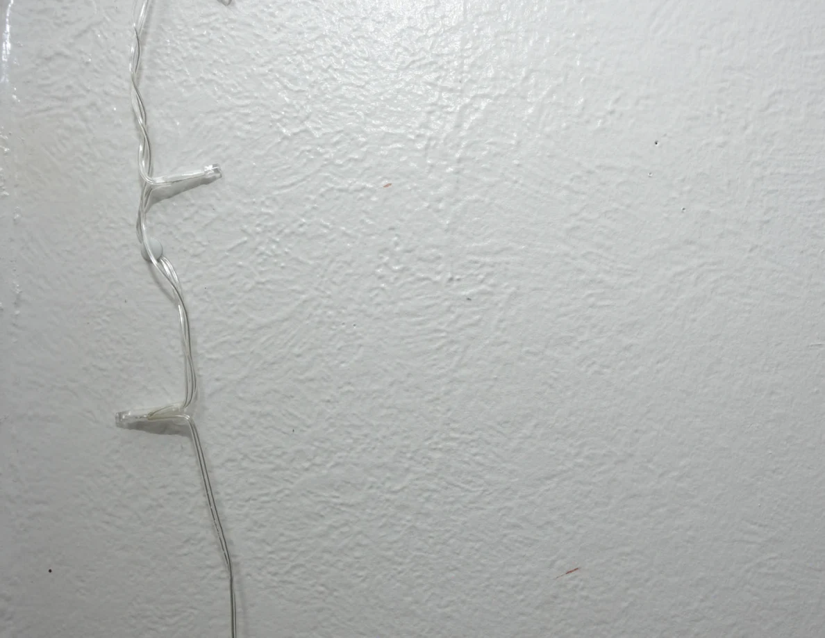 String-light cable against a pale textured wall.