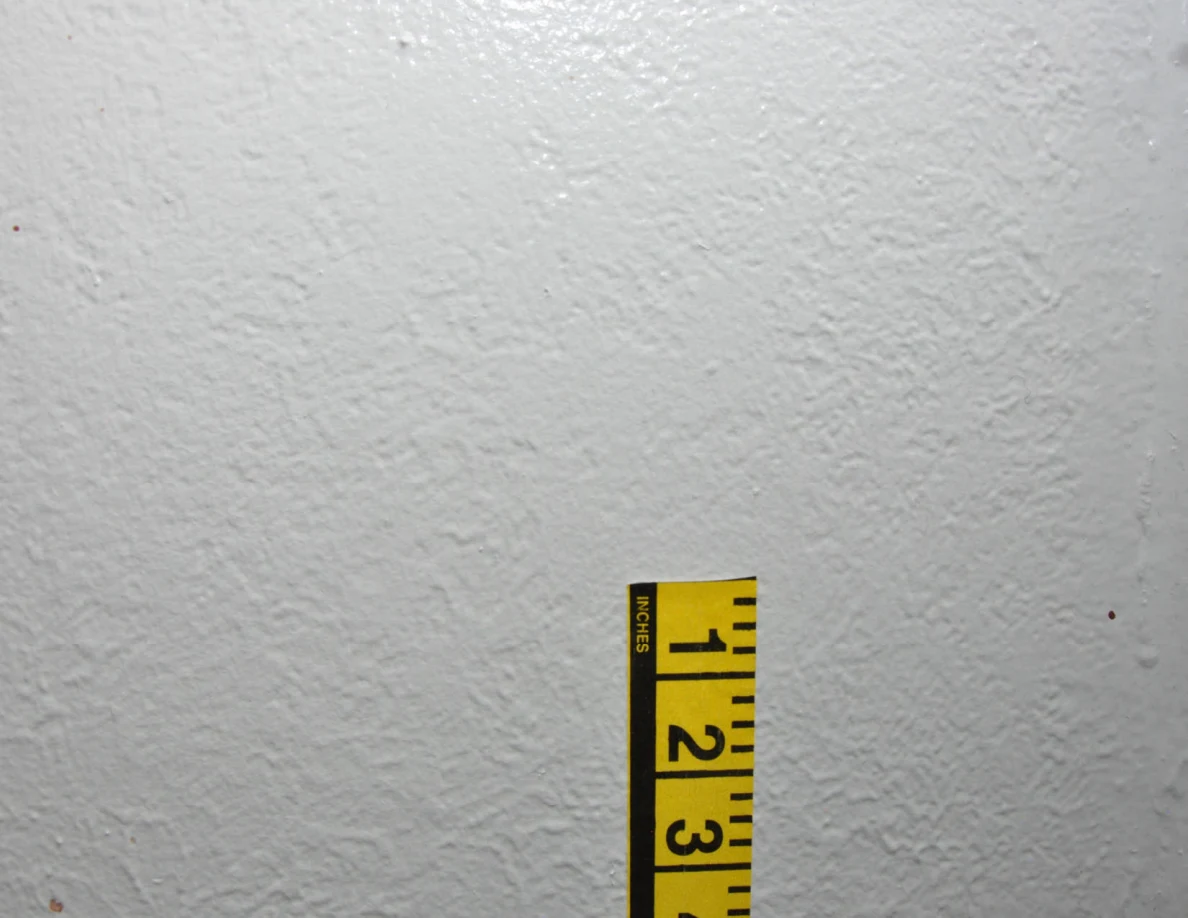 Yellow measuring tape beside small wall marks.