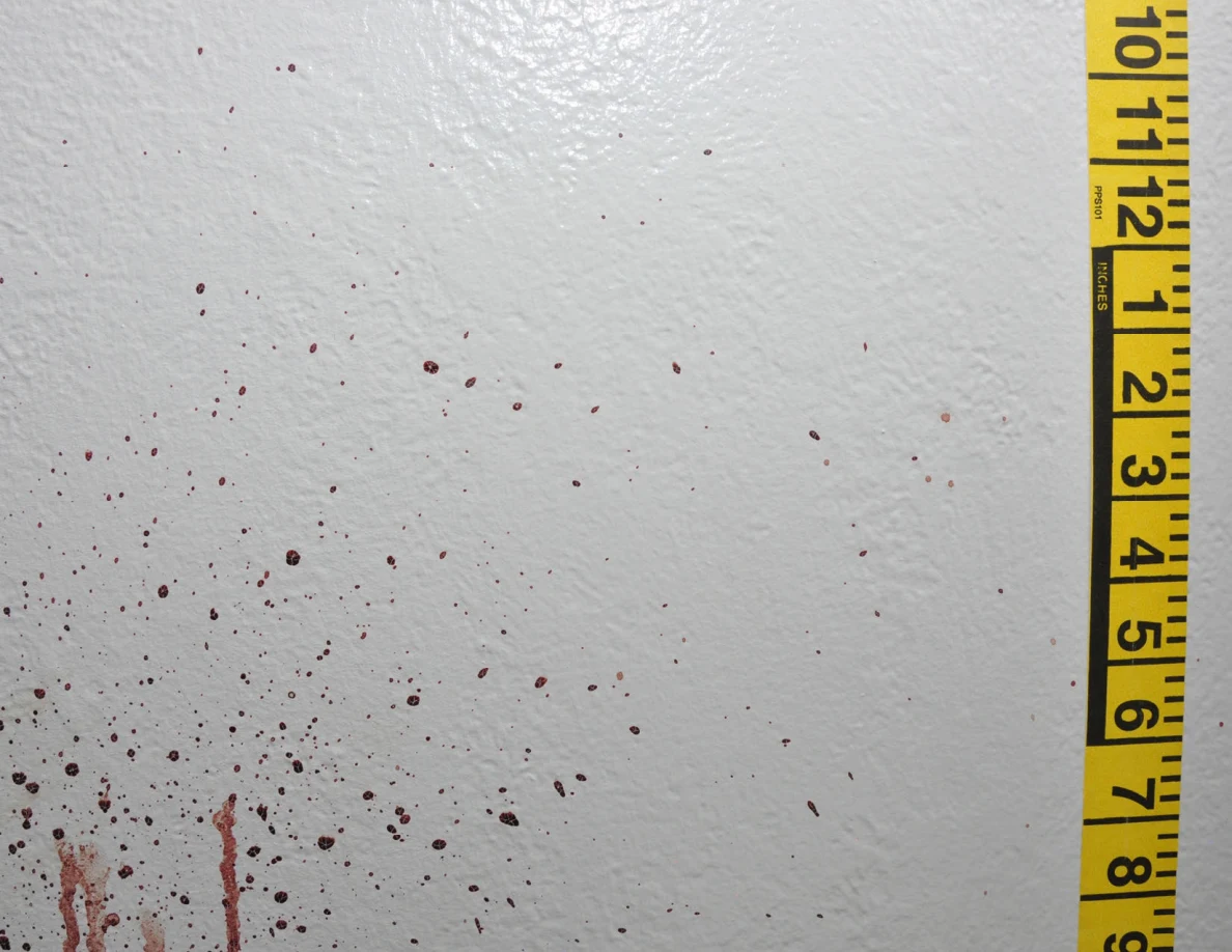 Reddish wall spots and vertical streaks beside yellow measuring tape.