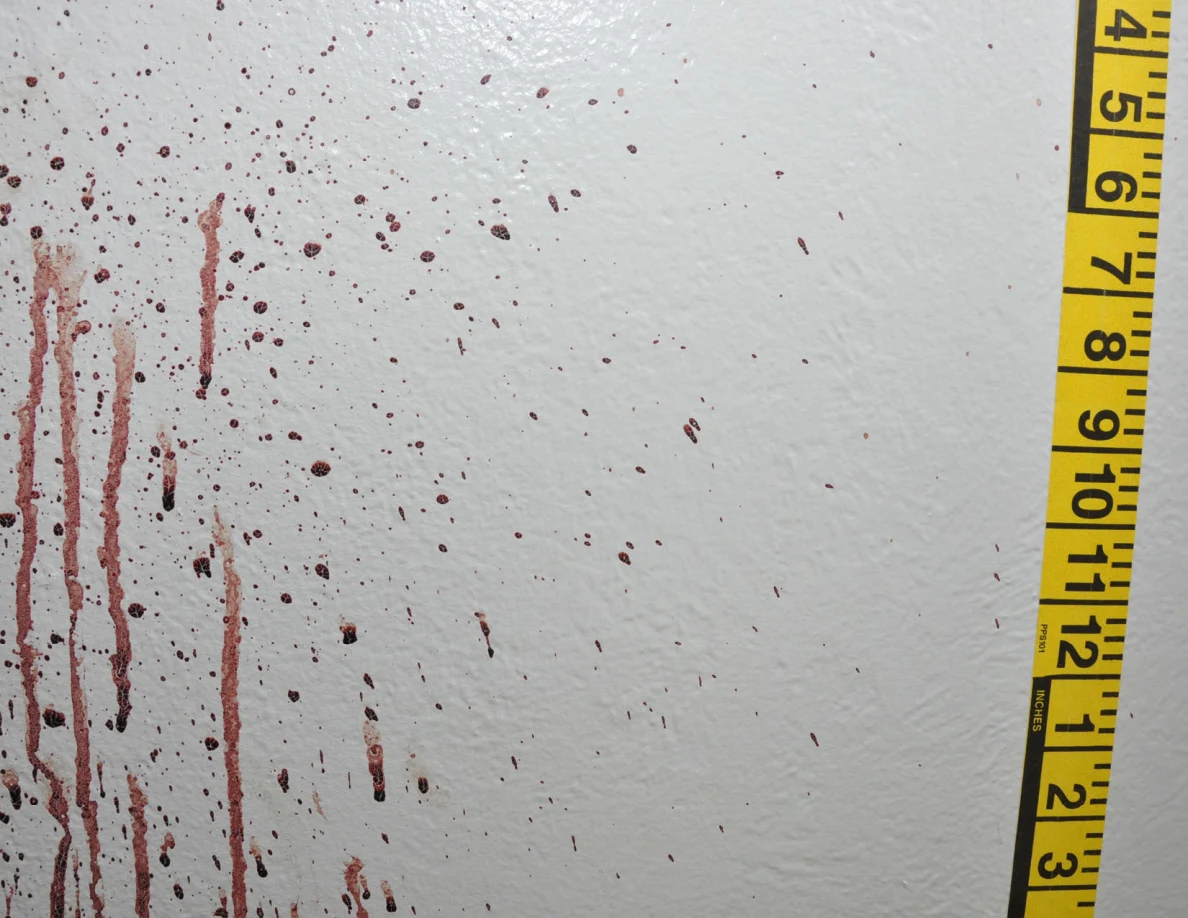 Reddish wall spots and vertical streaks beside yellow measuring tape.