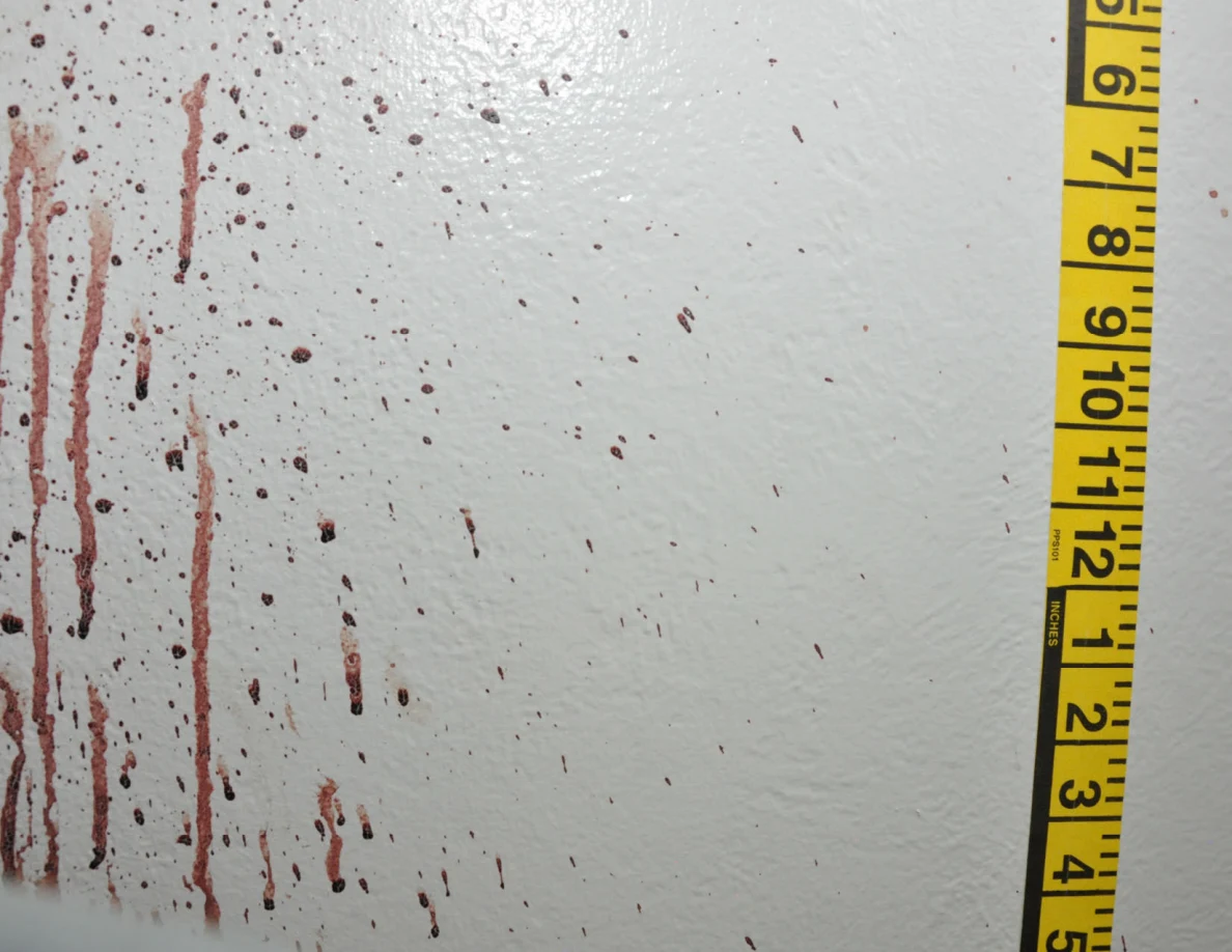 Reddish wall spots and vertical streaks beside yellow measuring tape.