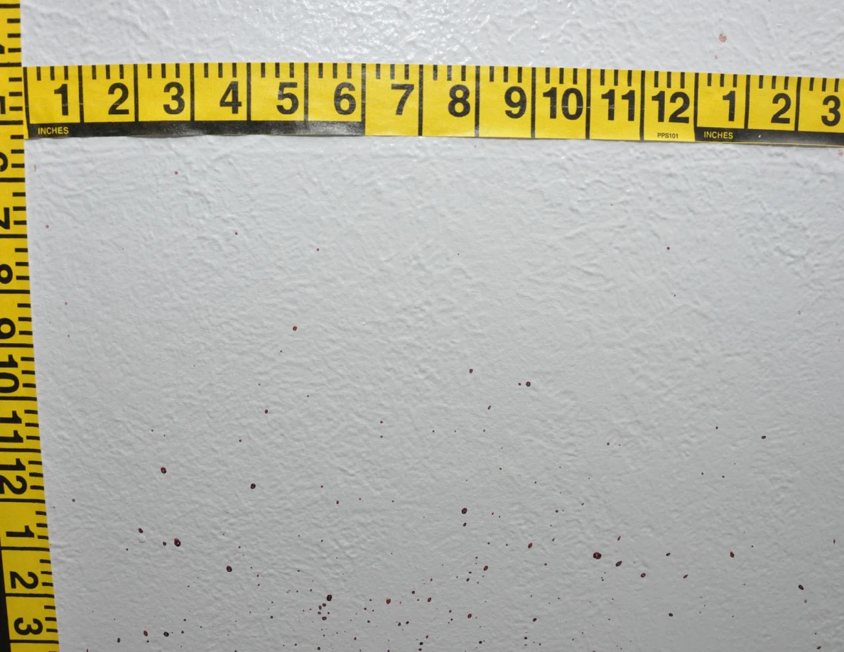 Intersecting yellow measuring tapes beside reddish wall spots.
