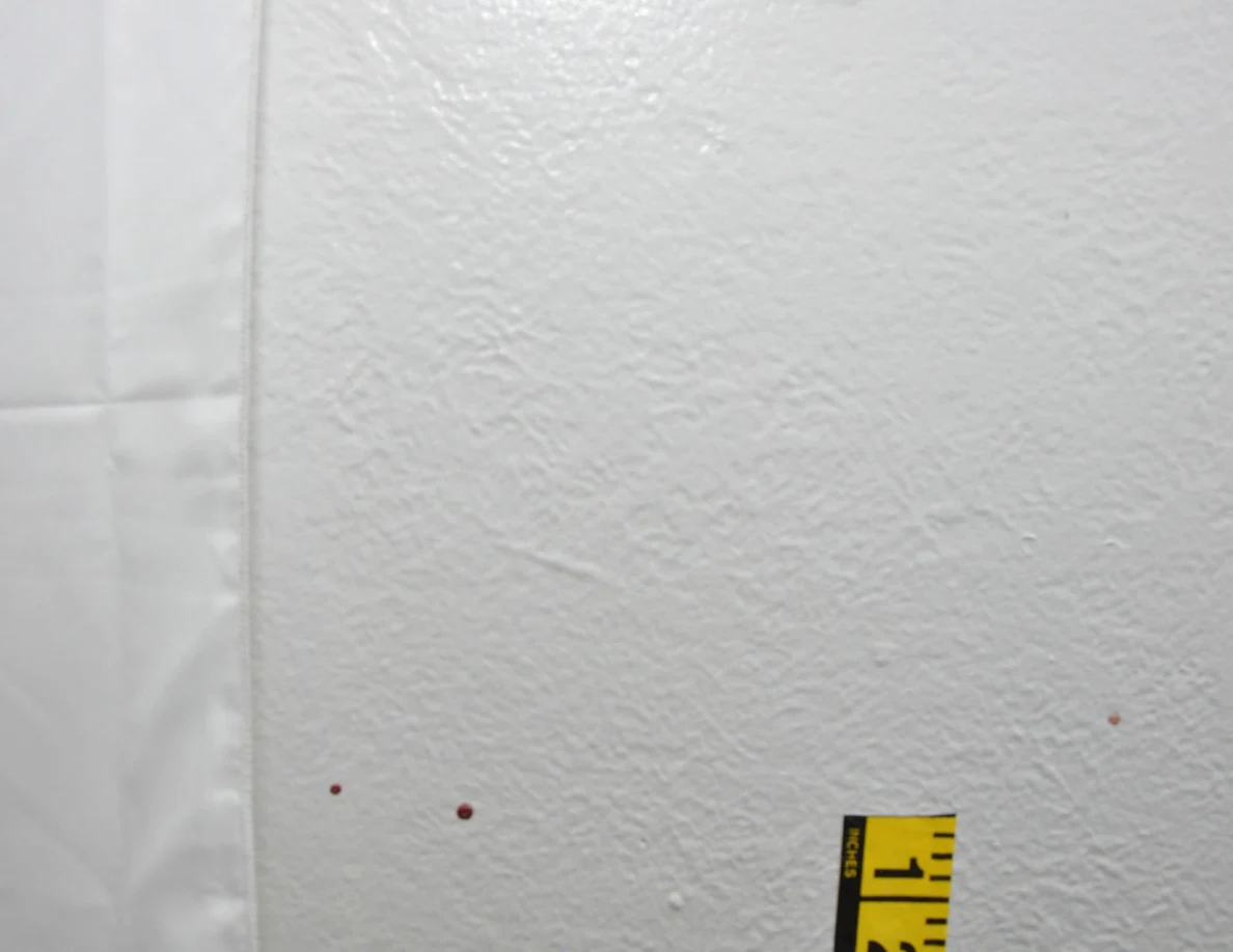 Reddish wall spots beside a fabric hanging and measuring tape.