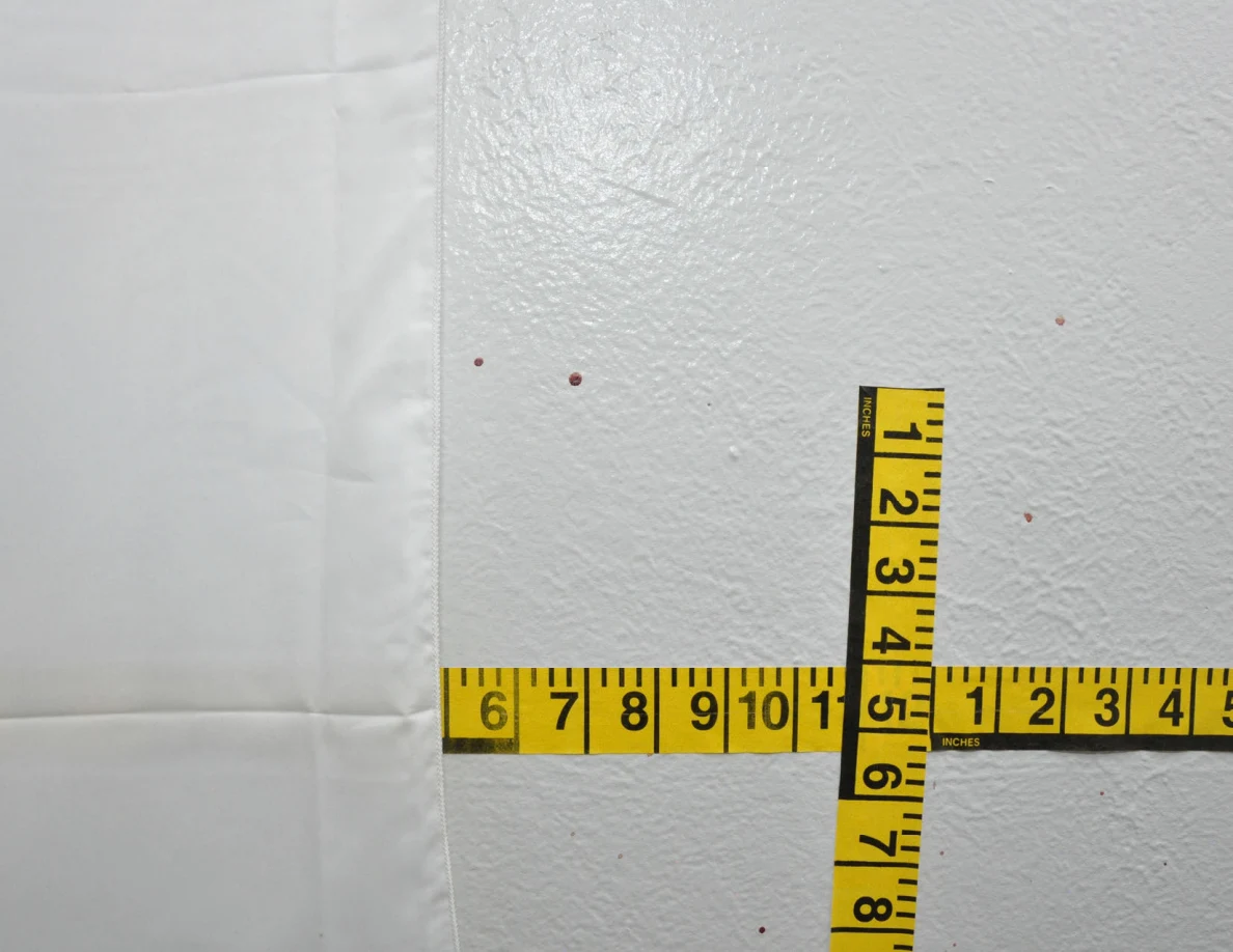 Intersecting yellow measuring tapes beside a fabric wall hanging.