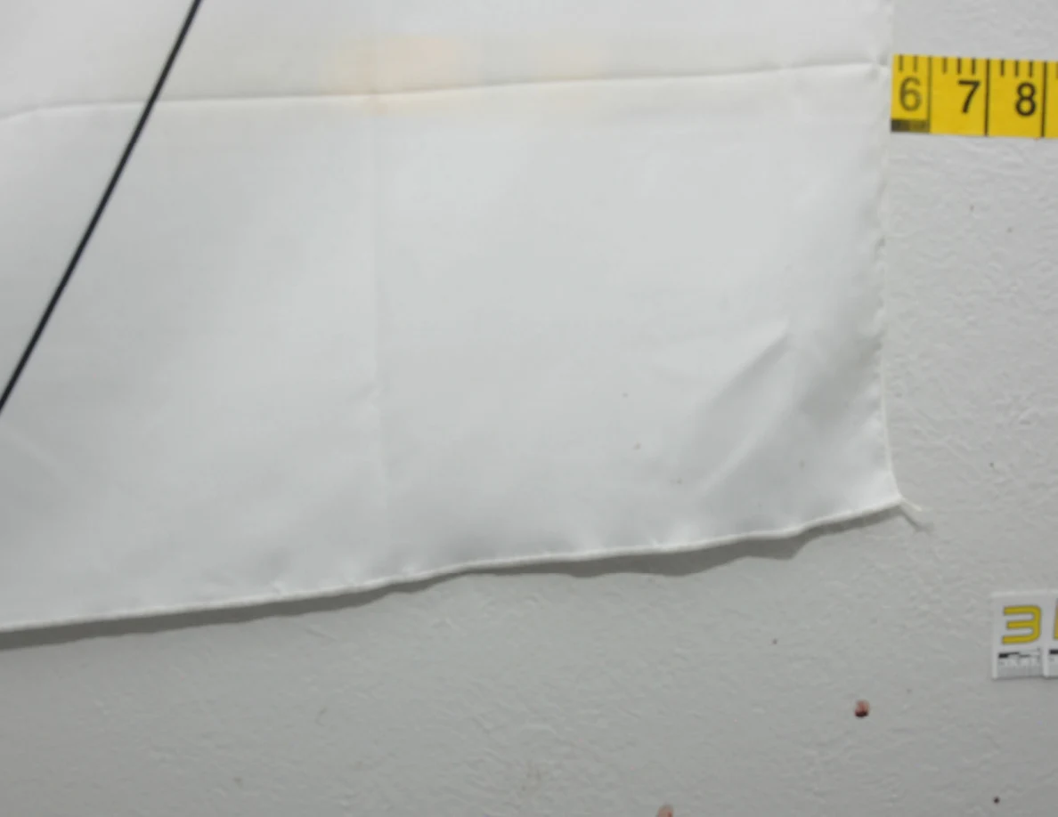 Lower corner of a fabric wall hanging beside measuring tape.