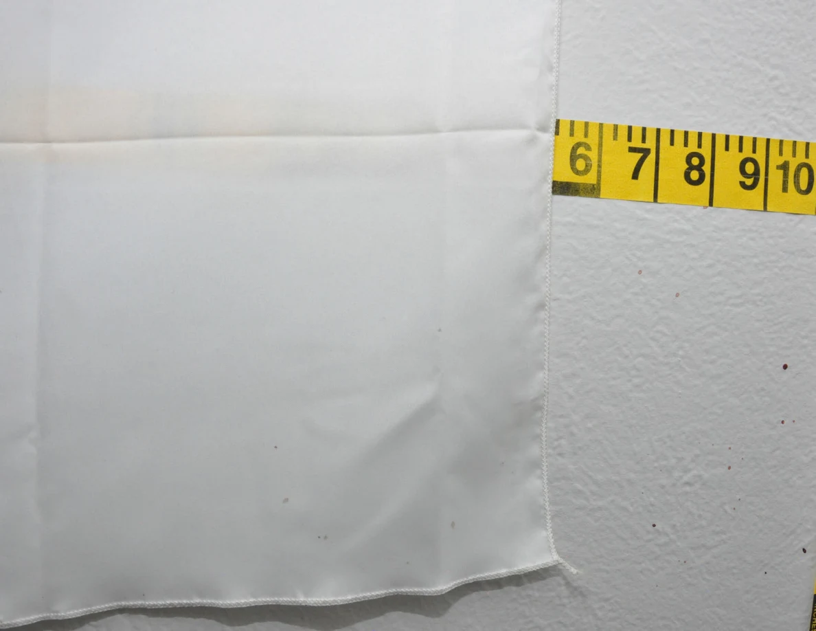 Fabric wall hanging edge beside yellow measuring tape.