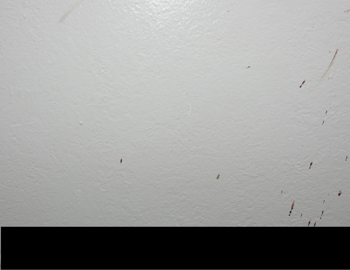 Small reddish wall marks above a black redaction.