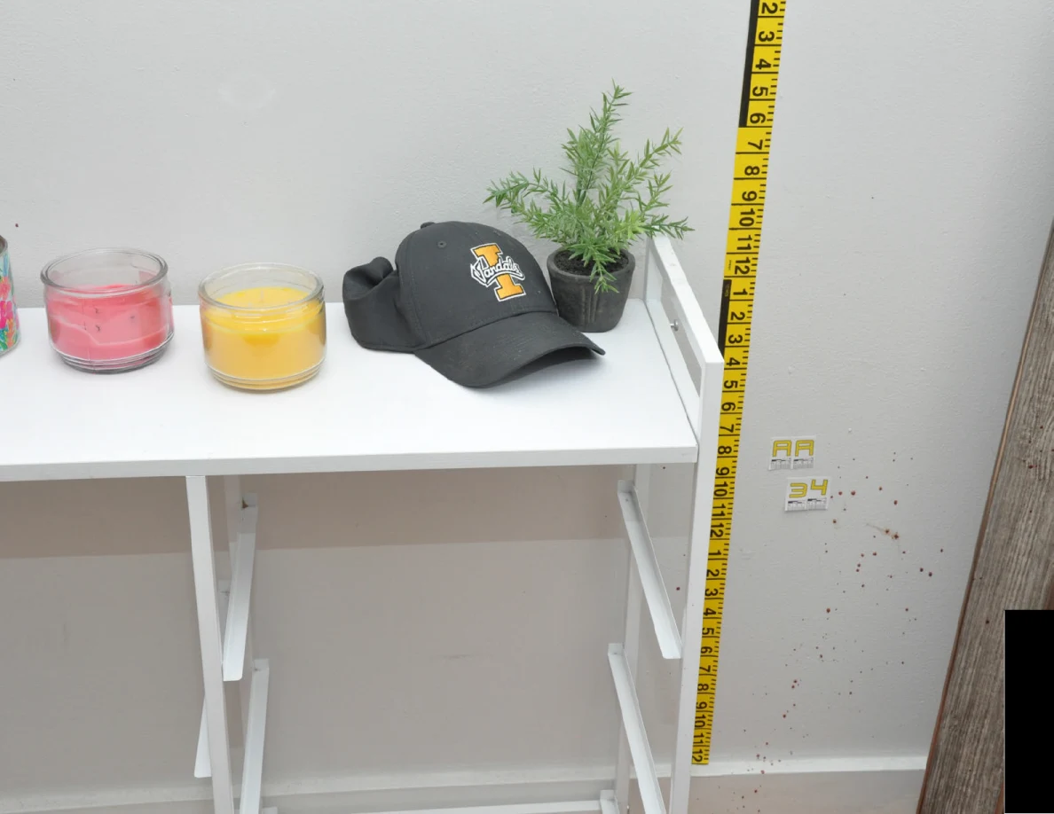 White cabinet with candles, a cap and a plant beside measuring tape and label AA34.
