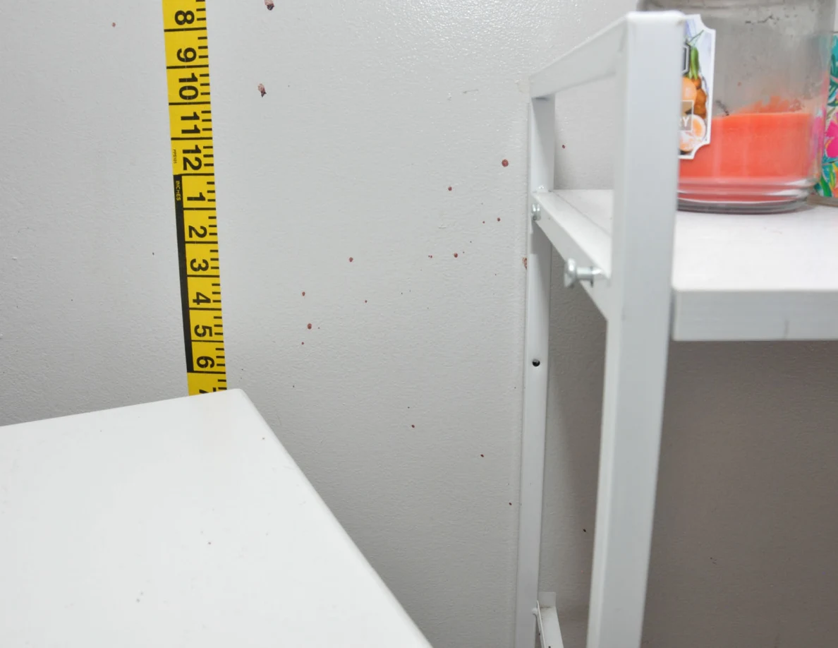Wall spots and vertical measuring tape beside cabinet candles.