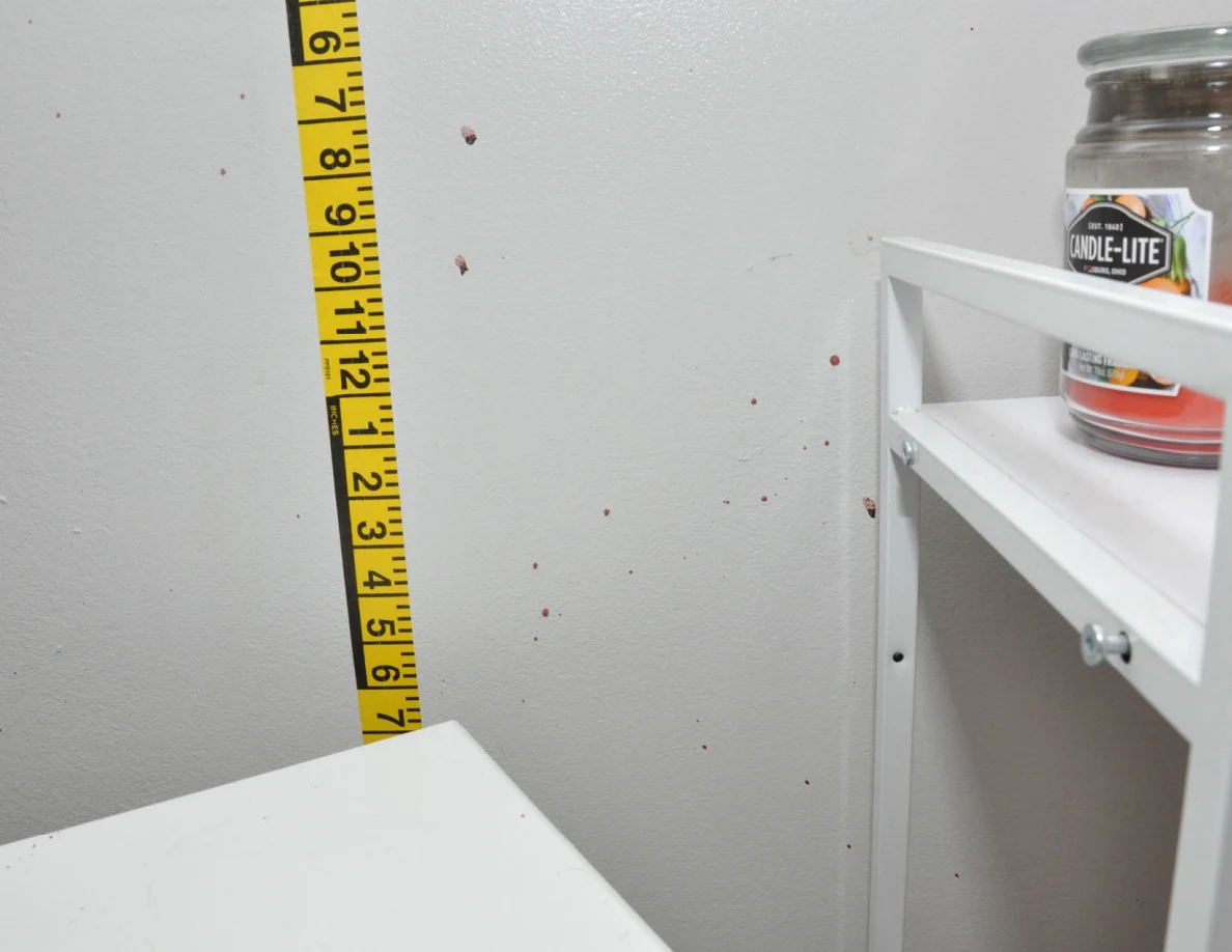 Wall spots beside measuring tape, a cabinet and a candle.