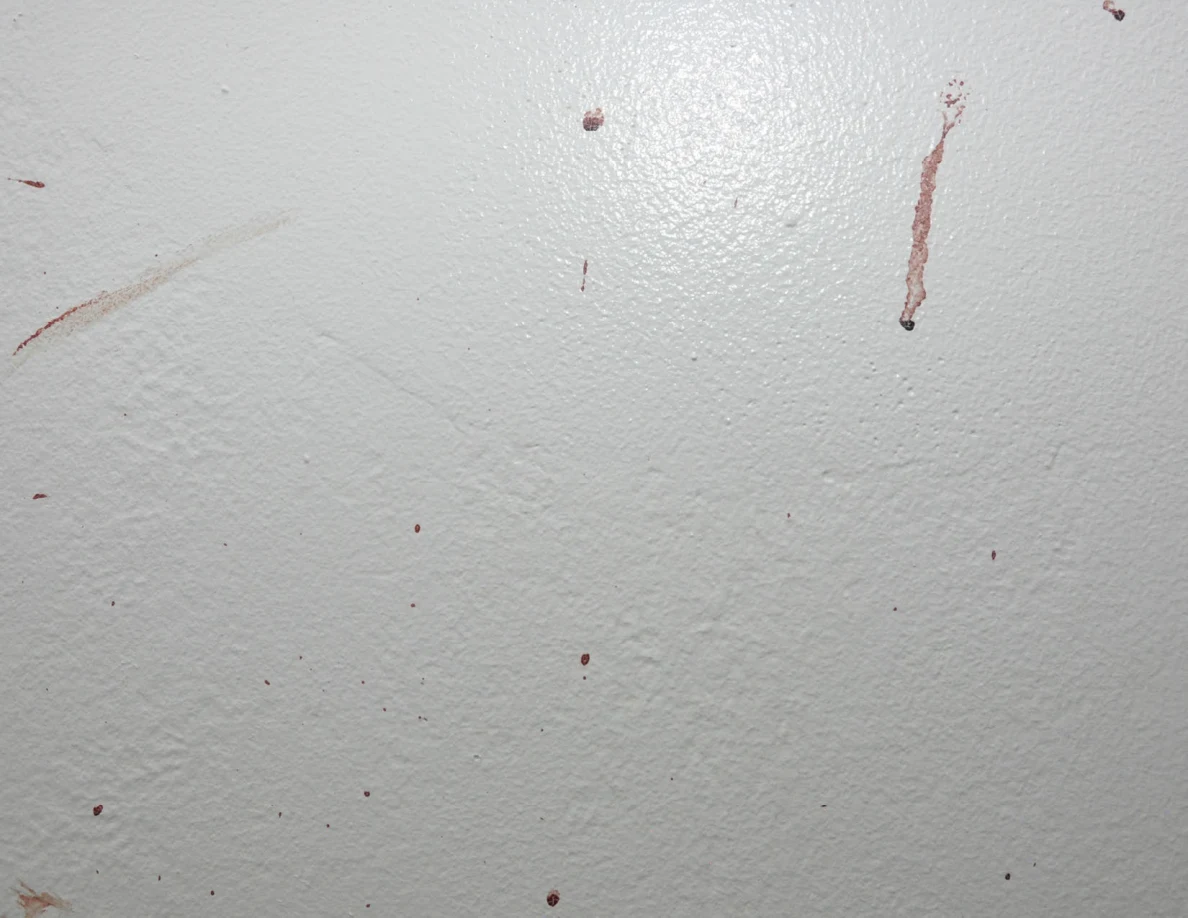 Close view of reddish drops and streaks on a white wall.