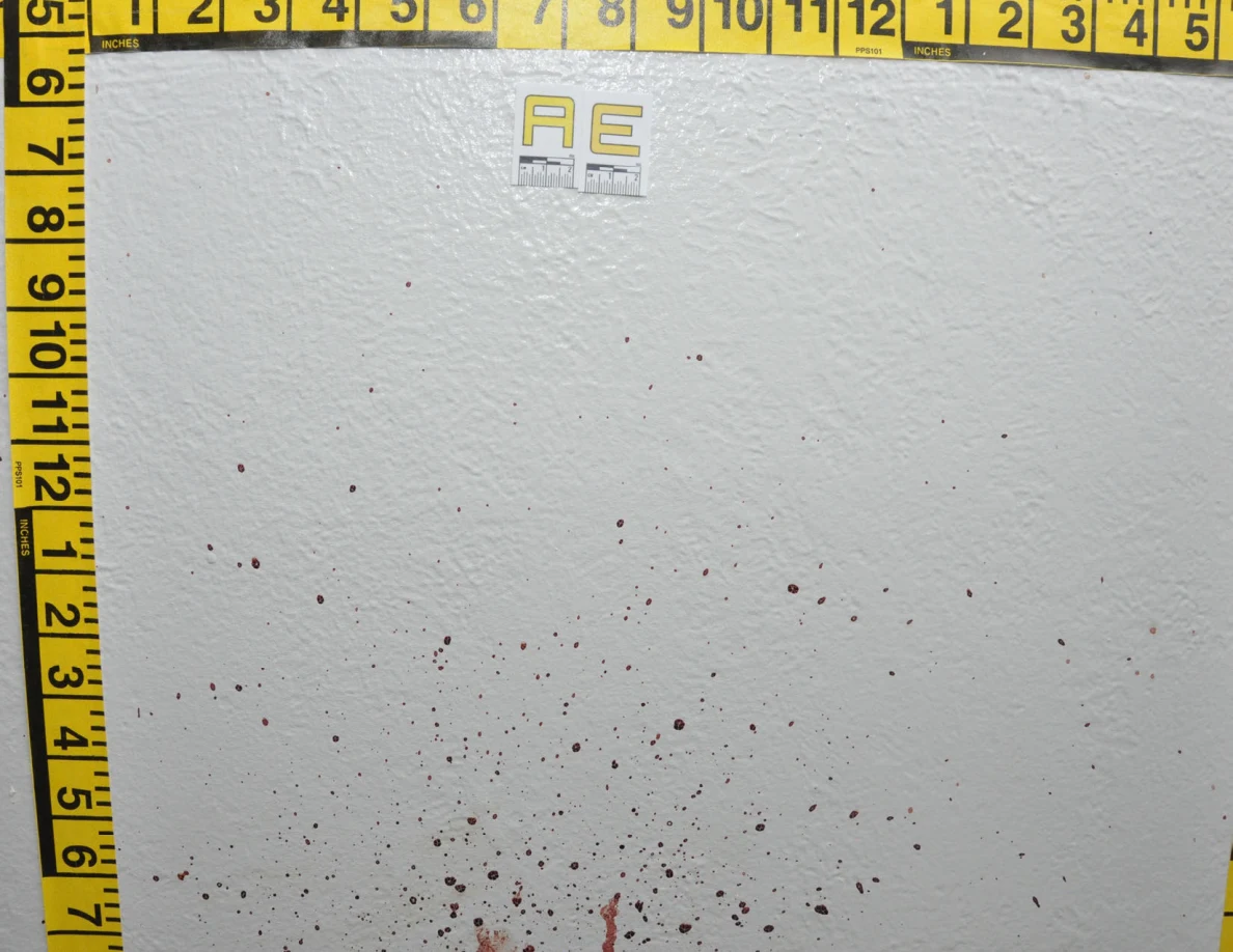 Reddish wall spots below label AE beside crossed yellow measuring tapes.