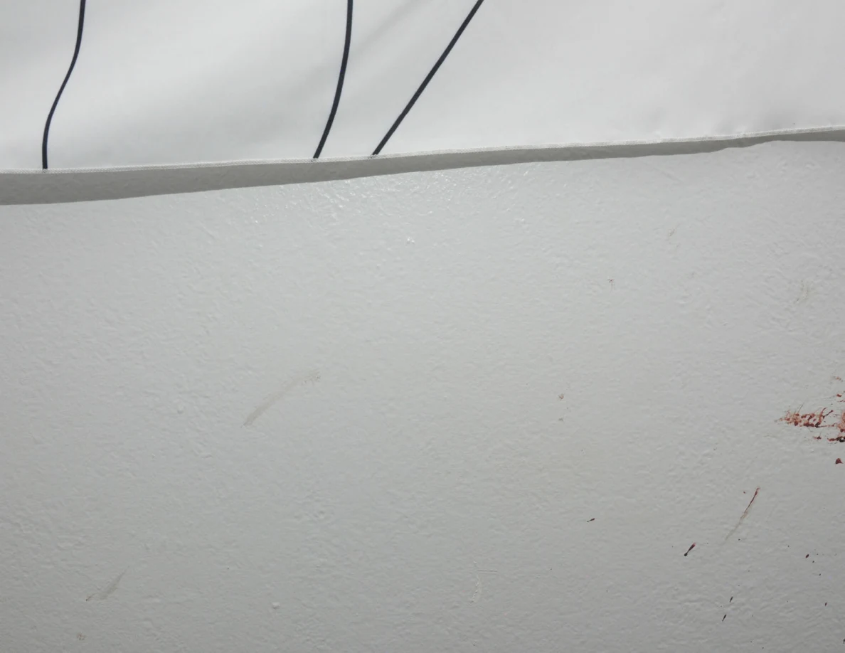 Faint wall smears and reddish marks below a fabric wall hanging.