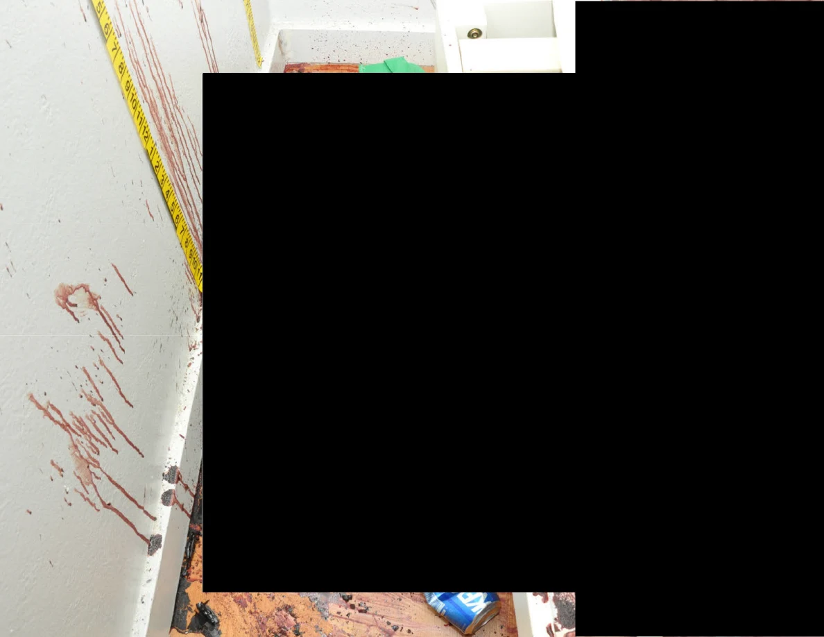Reddish wall streaks beside measuring tape and white furniture, with a large black redaction.
