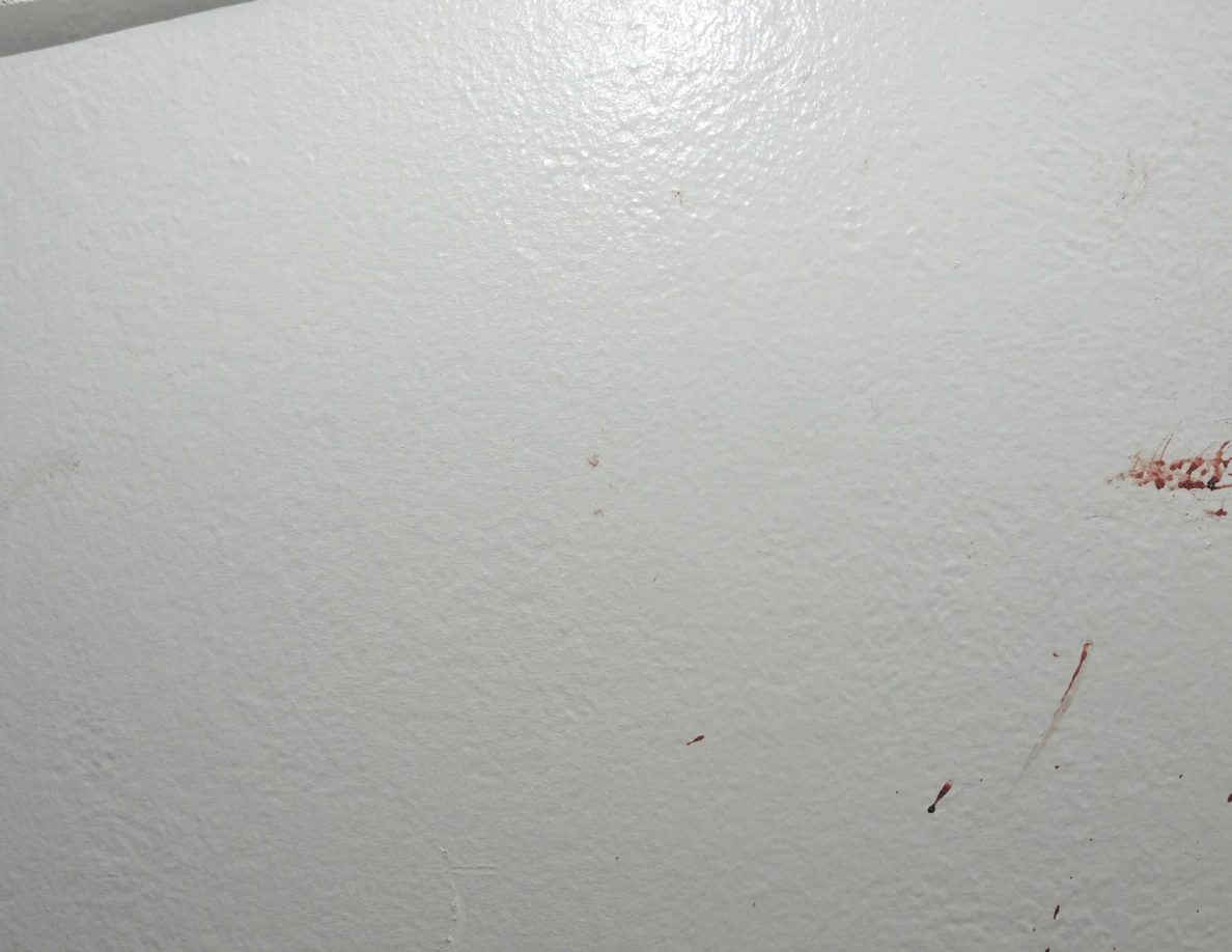 Faint marks and small reddish smears below a fabric hanging edge.