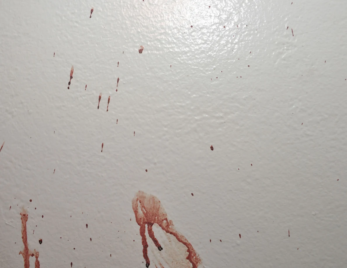Reddish wall smear with downward streaks below scattered spots.