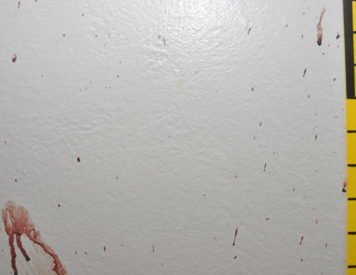 Small reddish wall streaks beside the edge of yellow measuring tape.