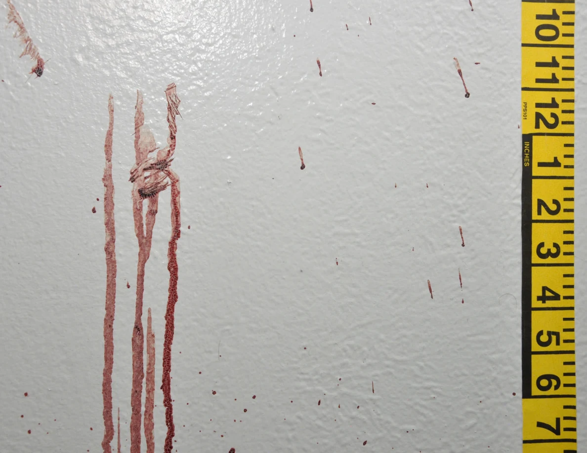 Long reddish wall streaks with a dark crossing mark beside measuring tape.