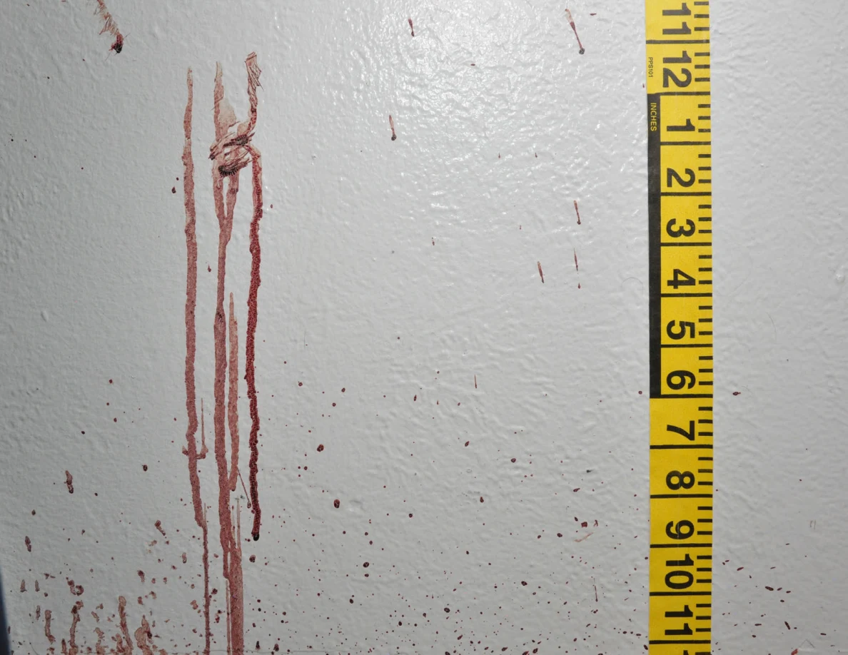 Long reddish wall streaks and small spots beside vertical measuring tape.