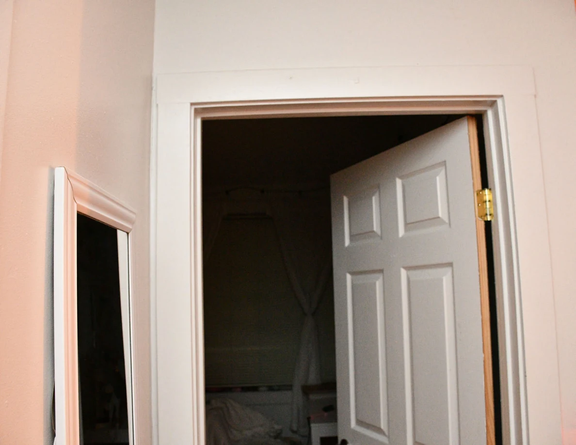 Upper doorway and open white bedroom door with a window visible beyond.