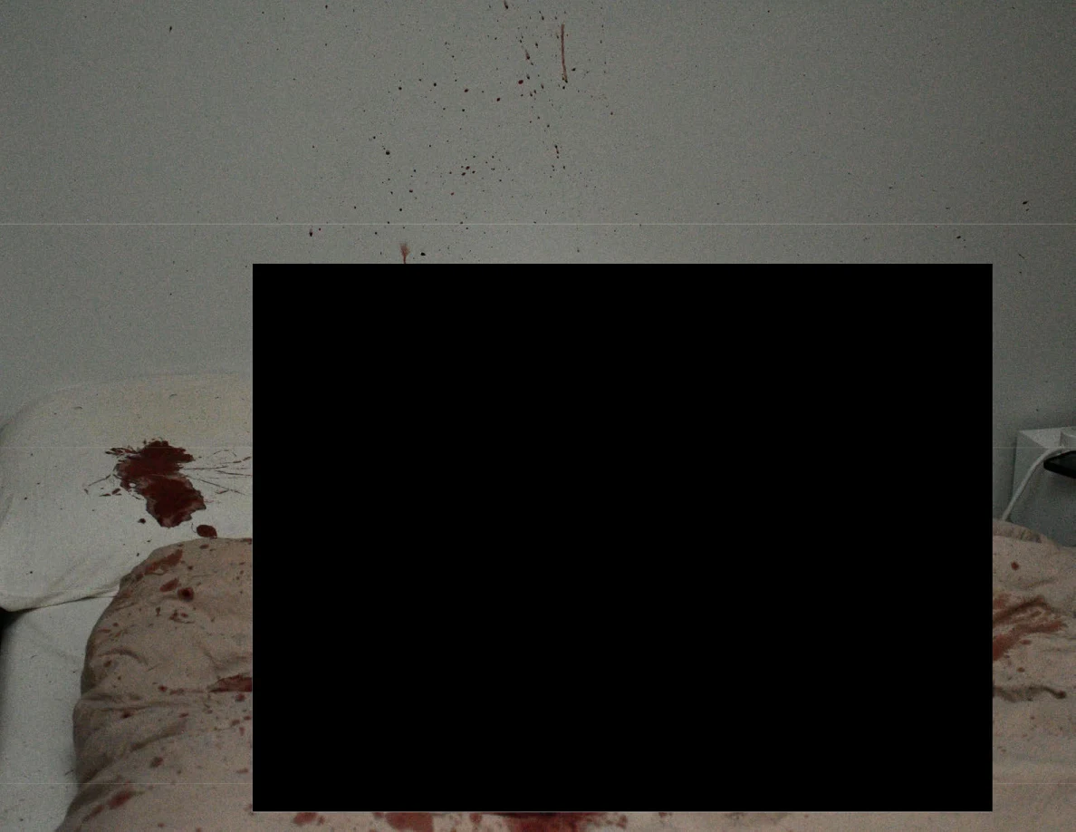 Reddish marks on bedding and wall around a large black redaction.