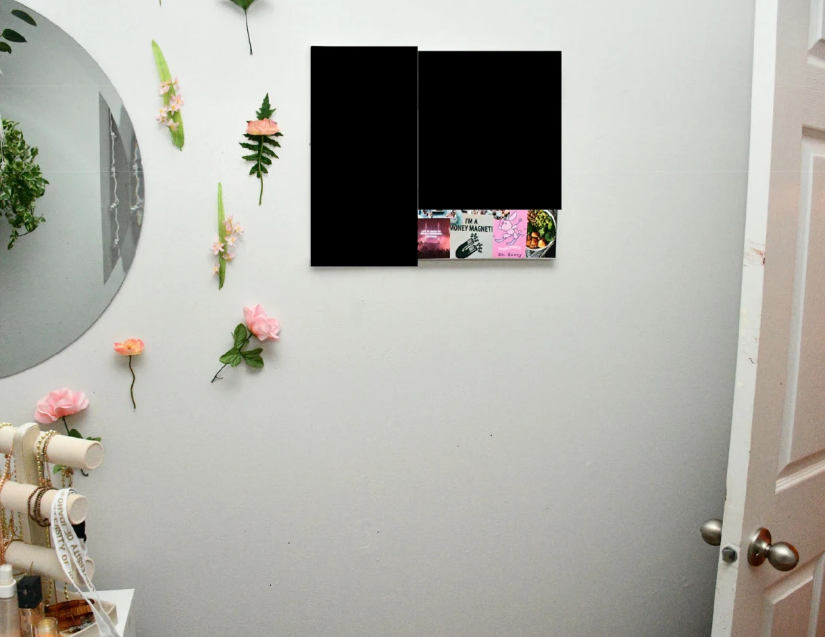 Wall flowers and jewelry stand beside round mirror, open door and redacted wall art.