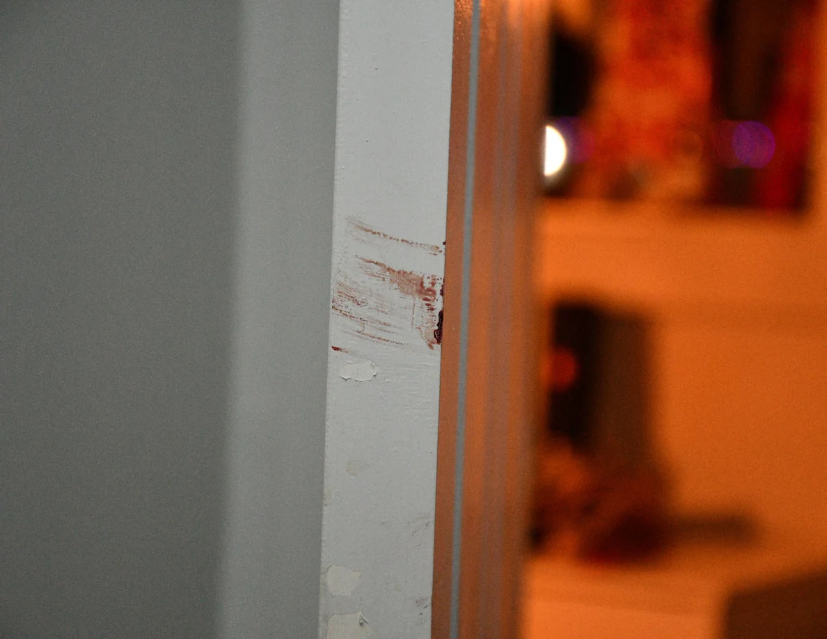 Close view of reddish smears on a white door-frame edge.