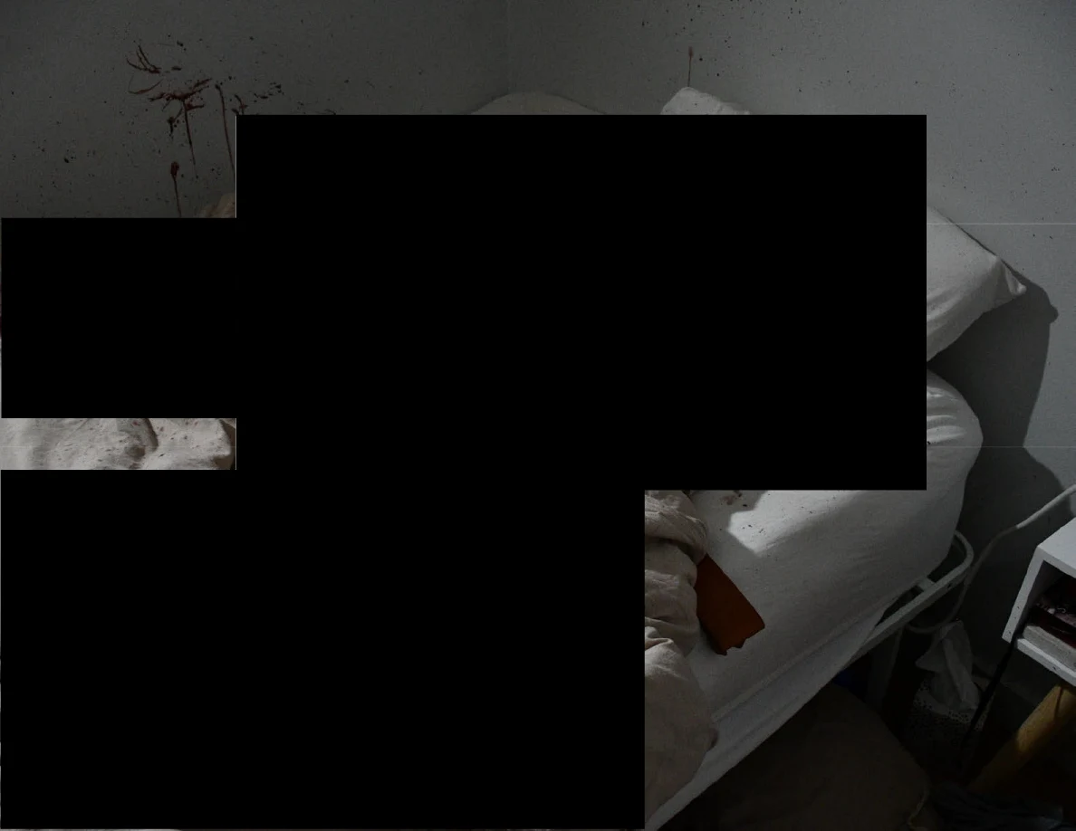 Bed edge and reddish wall marks surrounding large black redactions.