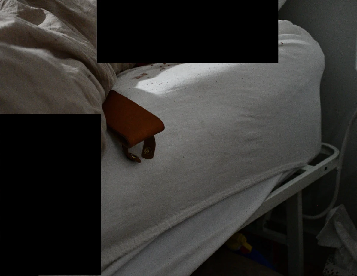 Brown leather sheath on a white mattress edge below a black redaction.