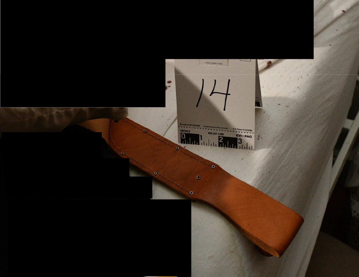 Brown leather sheath with metal fasteners beside evidence marker 14 on a white mattress, with black redactions.