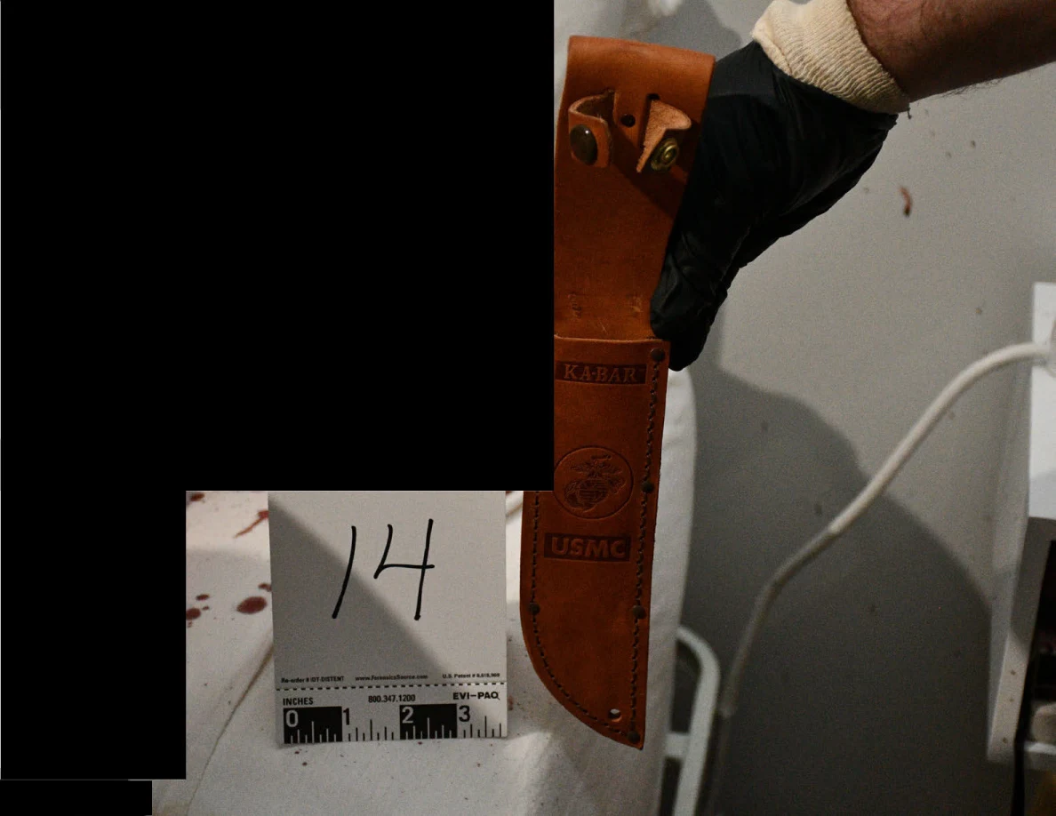 Black-gloved hand holding a brown leather sheath marked KA-BAR and USMC beside evidence marker 14, with black redactions.